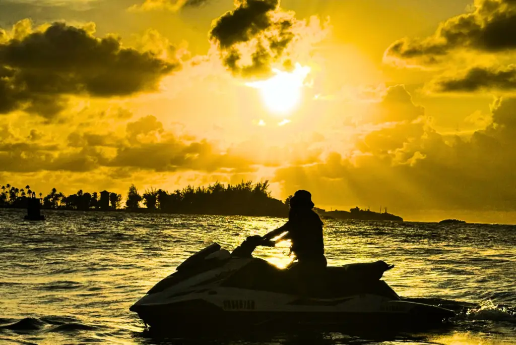 Jet ski rider silhouetted against a golden sunset in Isla Verde