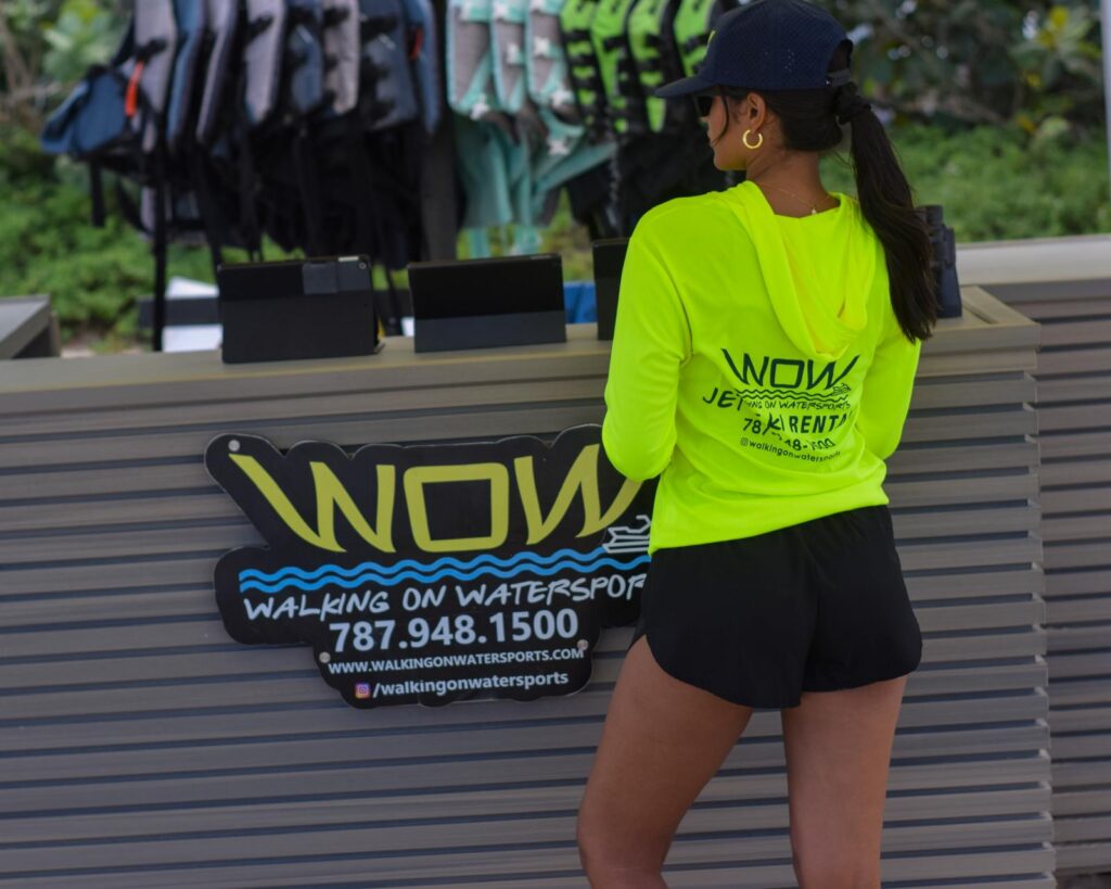 Walking On Watersports staff member in a neon WOW shirt at the Isla Verde jet ski rental counter
