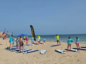 Surf students and WOW instructors standing with soft-top surfboards on Isla Verde beach